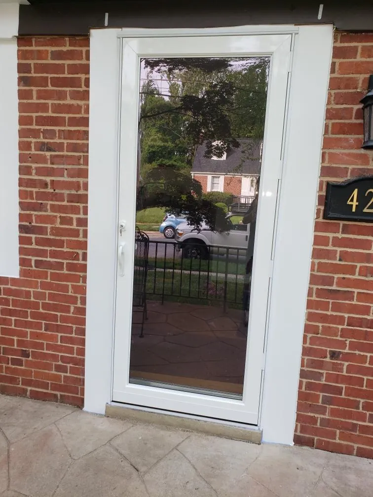 White full-view storm door installed in a red brick entryway