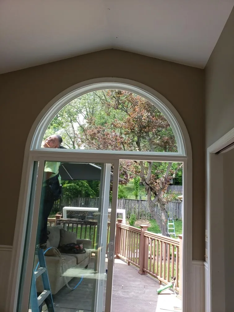 Interior view of an arched transom window above a sliding patio door