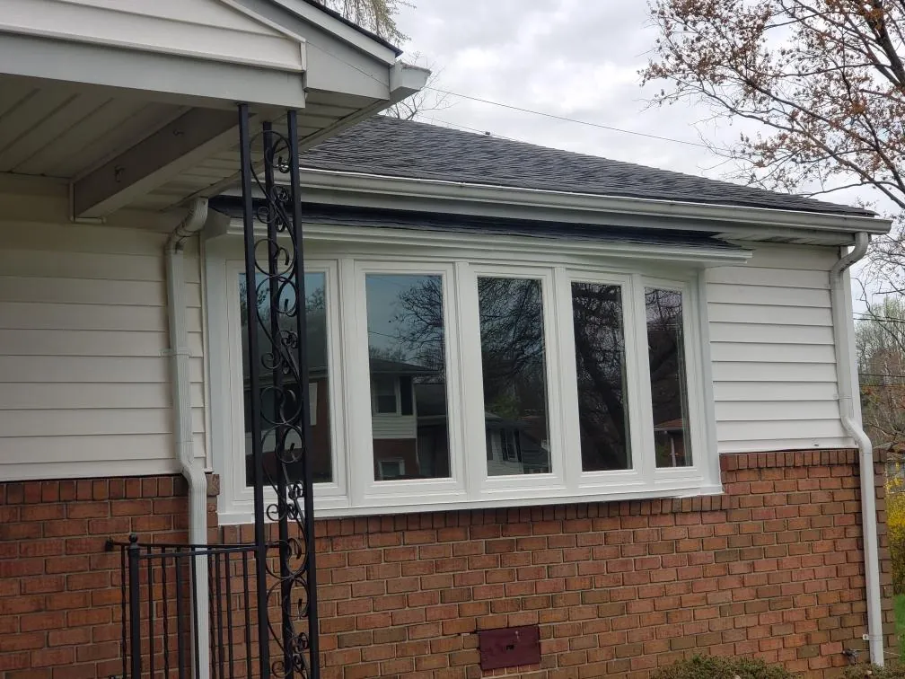 Five-lite bow window set into brick and siding beneath a shingled roofline