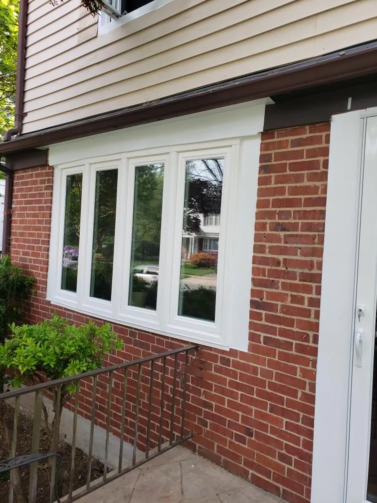 Four-lite casement bow window installed in a red brick wall with a new head trim