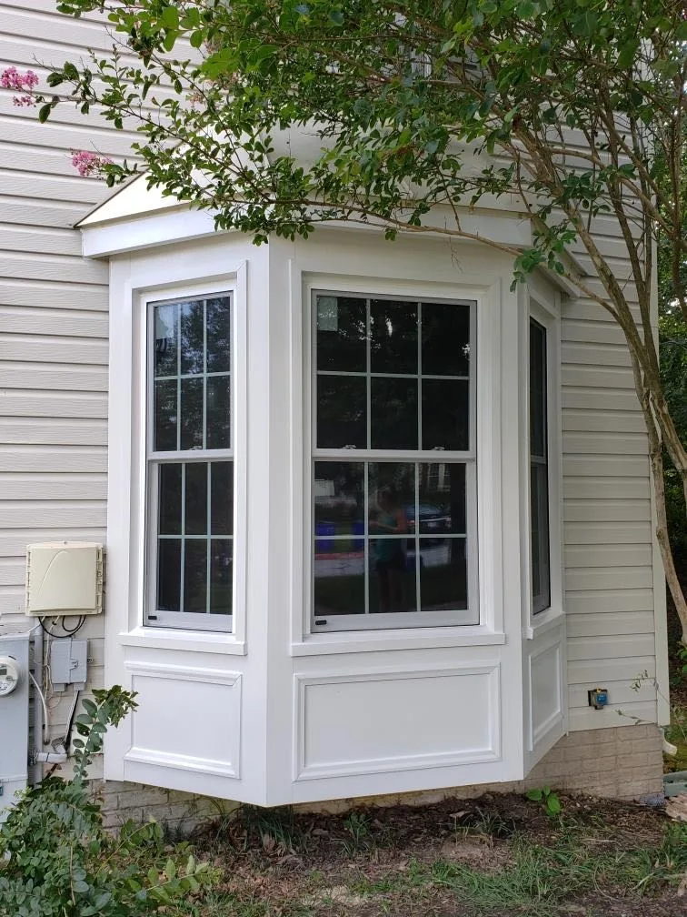 White bay window with colonial grilles and a panelled base on cream siding